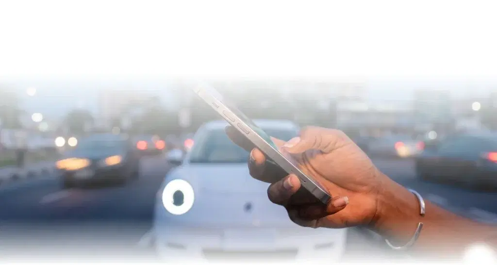 Hand holding a phone with the JéGO X app while driving through traffic